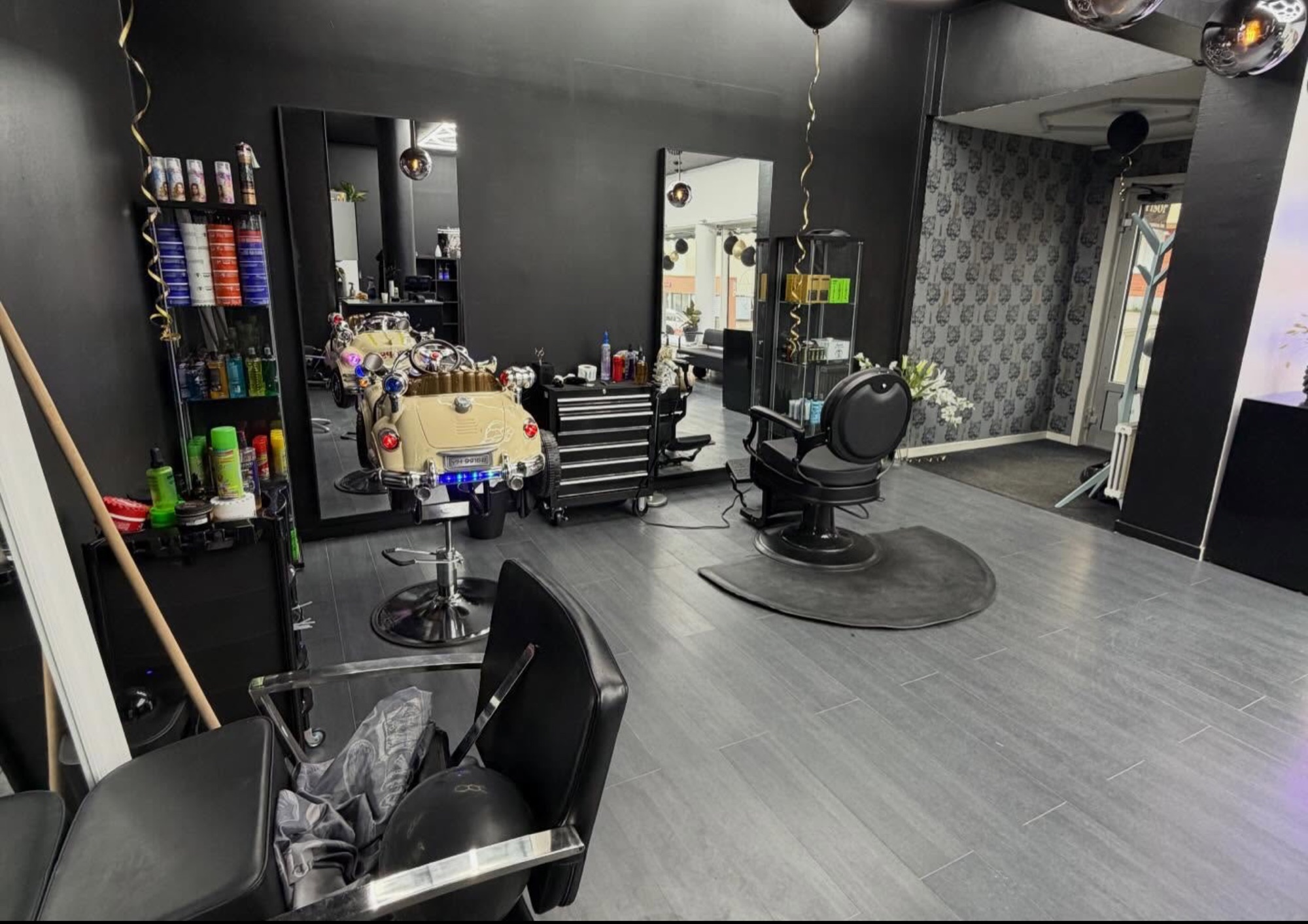 Barberarstol, spegel, produkthylla och en bilstol för barnklippning.